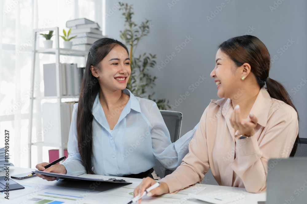 Two cheerful businesswomen collaborating and discussing ideas for a new project in a modern office, showcasing teamwork and professional growth Two cheerful businesswomen collaborating and discussing ideas for a new project in a modern office, showcasing teamwork and professional growth