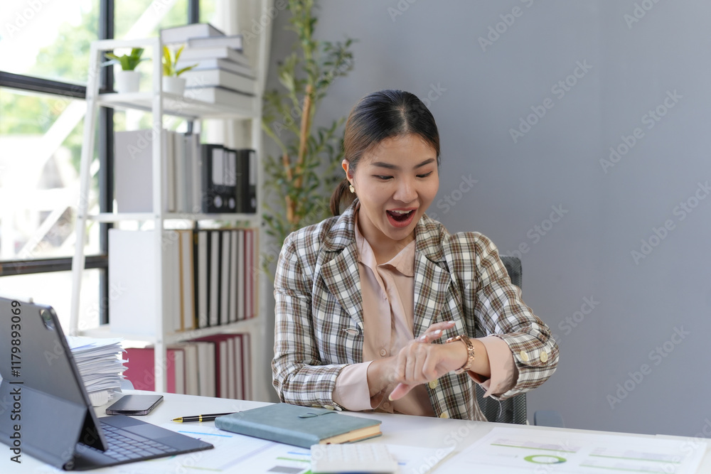 Asian businesswoman looking at her wristwatch with a surprised expression, realizing she is late for a meeting Asian businesswoman looking at her wristwatch with a surprised expression, realizing she is late for a meeting