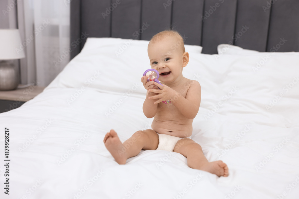 Cute little baby with rattle on bed indoors Cute little baby with rattle on bed indoors