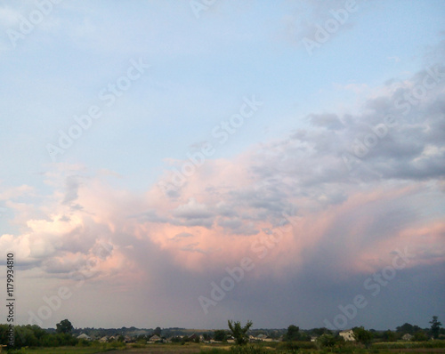 Countryside view with dramatic pink and gray clouds during sunset over fields and rural landscape. Nature and weather concept for design and print. photo