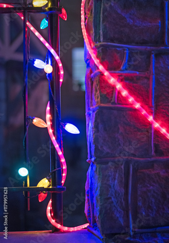 Vintage Christmas holiday lights decorate a stone wall and iron gate at night