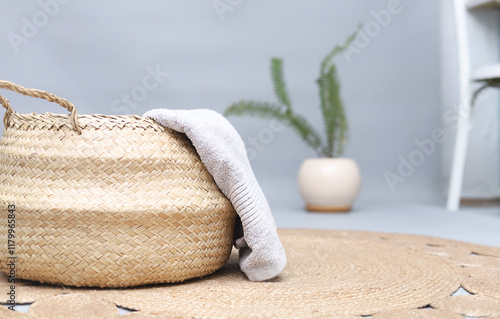 Straw wicker basket and natural cotton towel on handmade jute rug. Stylish interior item. Eco design for bathroom.Space for text.