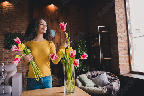 Young woman enjoying floral arrangement in cozy home with natural light streaming in photo