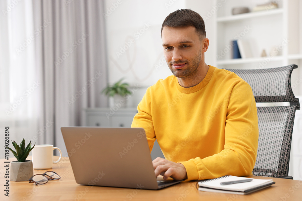 Programmer working on laptop at wooden desk indoors Programmer working on laptop at wooden desk indoors
