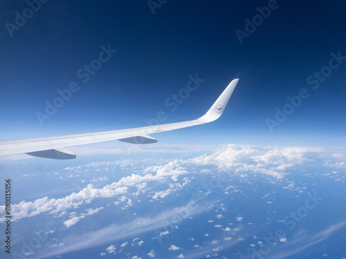 Airplane wing flying above clouds on sunny day photo