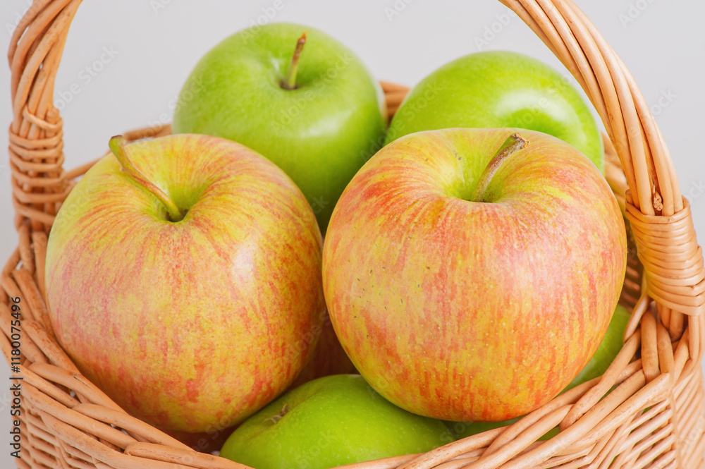 Two different varieties of apples in a wicker basket on a gray background. Fruits, apples.
