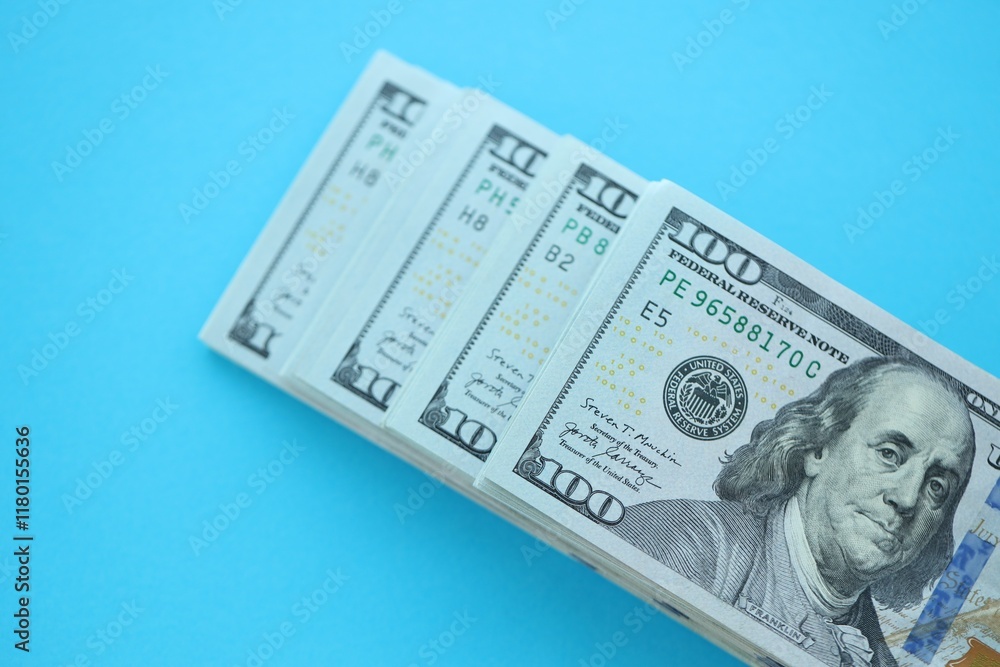 Big amount of hundred dollar bills in thick stack lies on bright blue color paper background Big amount of hundred dollar bills in thick stack lies on bright blue color paper background