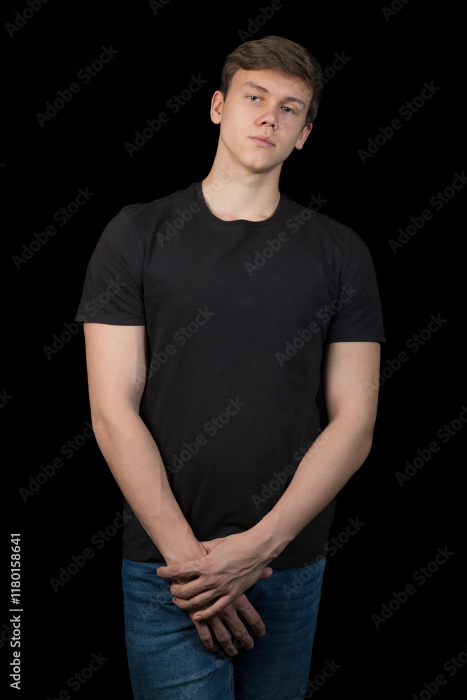A young man in a black T-shirt on a black background. A young man in a black T-shirt on a black background.