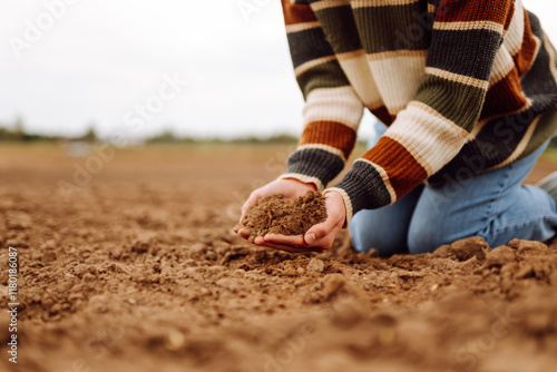 Women's hands sort through black soil in the field. Farmer is checking soil quality before sowing. Ecology, agriculture concept. photo