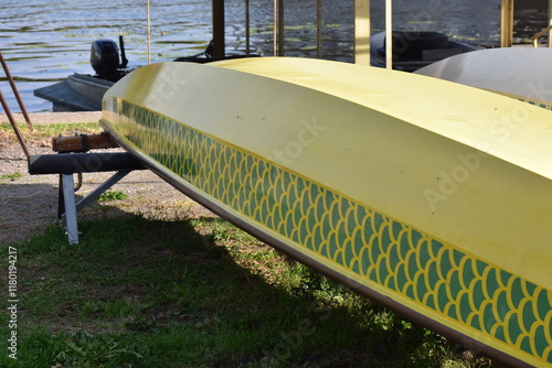 Yellow dragon boat on the shore of a lake upside down in the park in summer photo