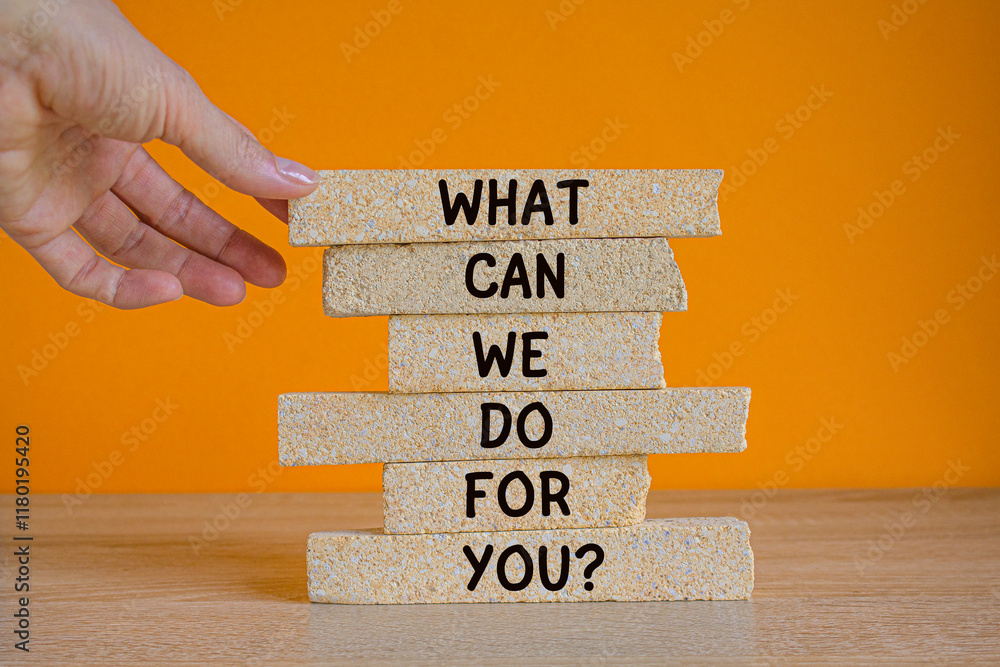 Support symbol. Concept words What can we do for you on brick blocks on a wooden table orange background. Businessman hand. Business motivational and support concept.