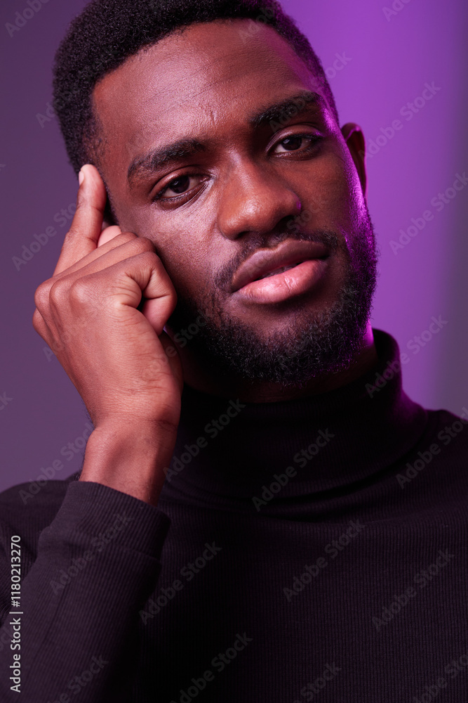 Portrait of a thoughtful young Black man in a turtleneck sweater with a serious expression against a purple background Emotional and stylish concept Portrait of a thoughtful young Black man in a turtleneck sweater with a serious expression against a purple background Emotional and stylish concept