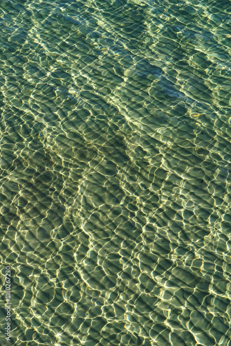 Pattern of waves and sun reflections on the surface of emerald sea water photo