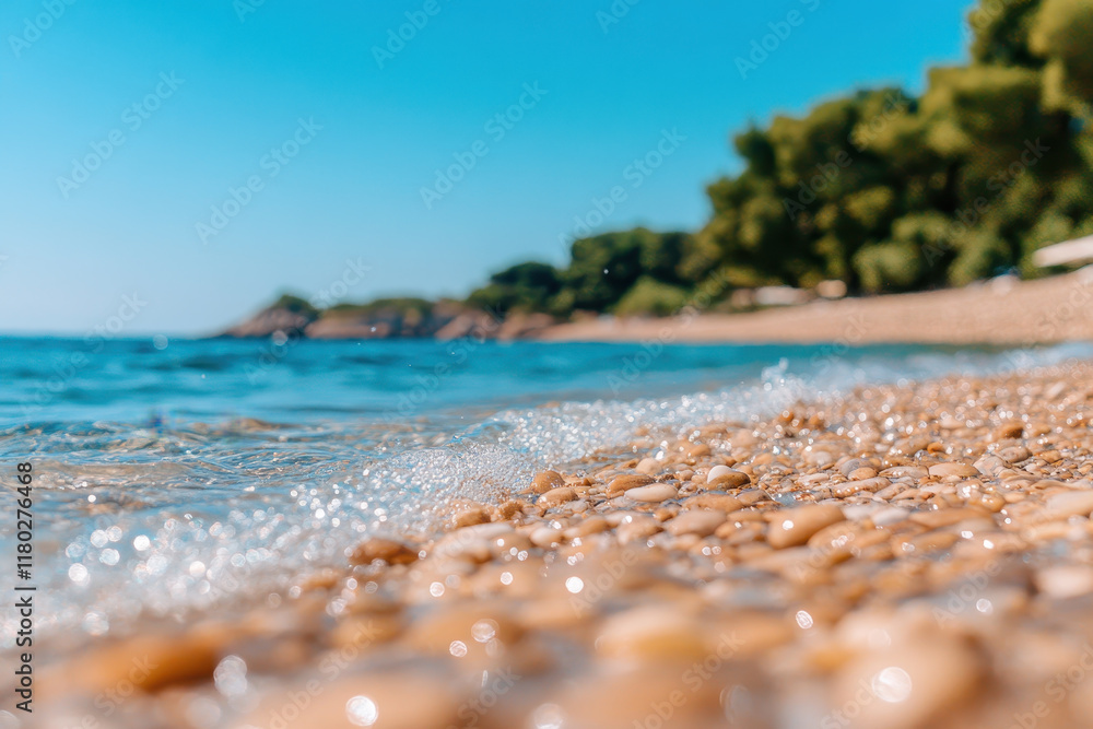 Close-up of a pebble beach with gentle waves, clear blue water, and tree-lined shoreline under a bright summer sky Close-up of a pebble beach with gentle waves, clear blue water, and tree-lined shoreline under a bright summer sky