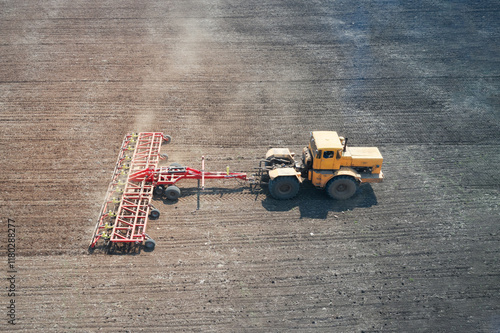 Spring sowing campaign. A single tractor with a trailed combined machine harrows arable land. Drone footage. photo