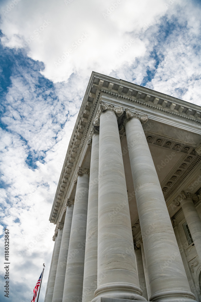 Upward view of classical columns under a blue sky with fluffy clouds. Upward view of classical columns under a blue sky with fluffy clouds.