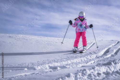 A young skier in colorful gear glides through snow under a sunny sky, showcasing the joy of winter sports and the freedom that people of all ages can experience, Montgenevre ski village, Alps, France photo