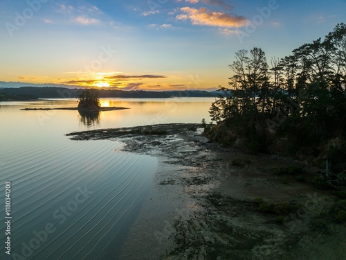 Sunrise over tranquil bay; calm water reflects golden sky; dramatic shoreline. Mahurangi East, Warkworth, Auckland, New Zealand photo