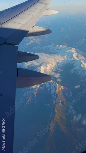 View from the airplane window over mountain peaks with snow.	