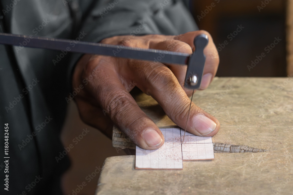 Artisan - Craftmand sawing a piece of metal with a artesanal saw Artisan - Craftmand sawing a piece of metal with a artesanal saw