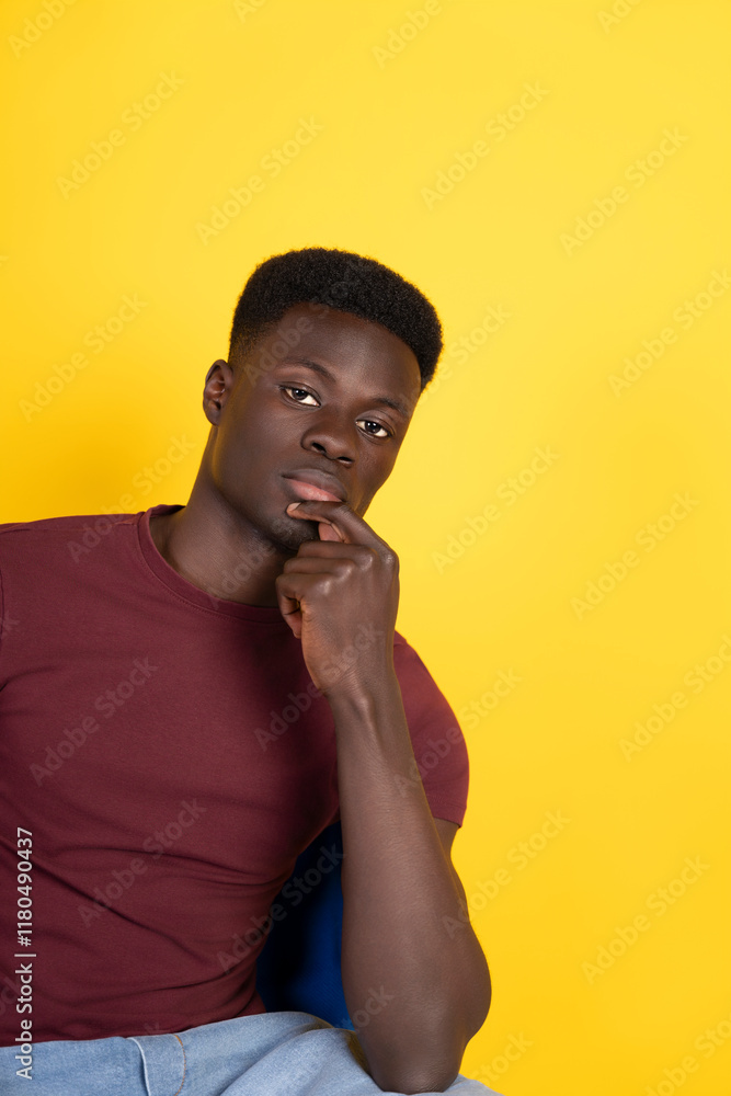 Pensive young man sitting and thinking on yellow background Pensive young man sitting and thinking on yellow background