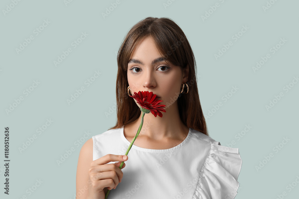 Beautiful young woman with red gerbera flower on grey background Beautiful young woman with red gerbera flower on grey background