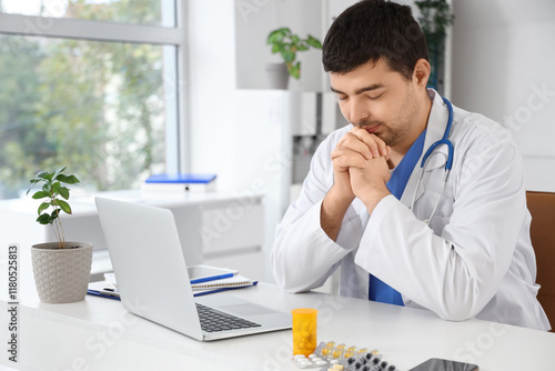 Male doctor praying at work...