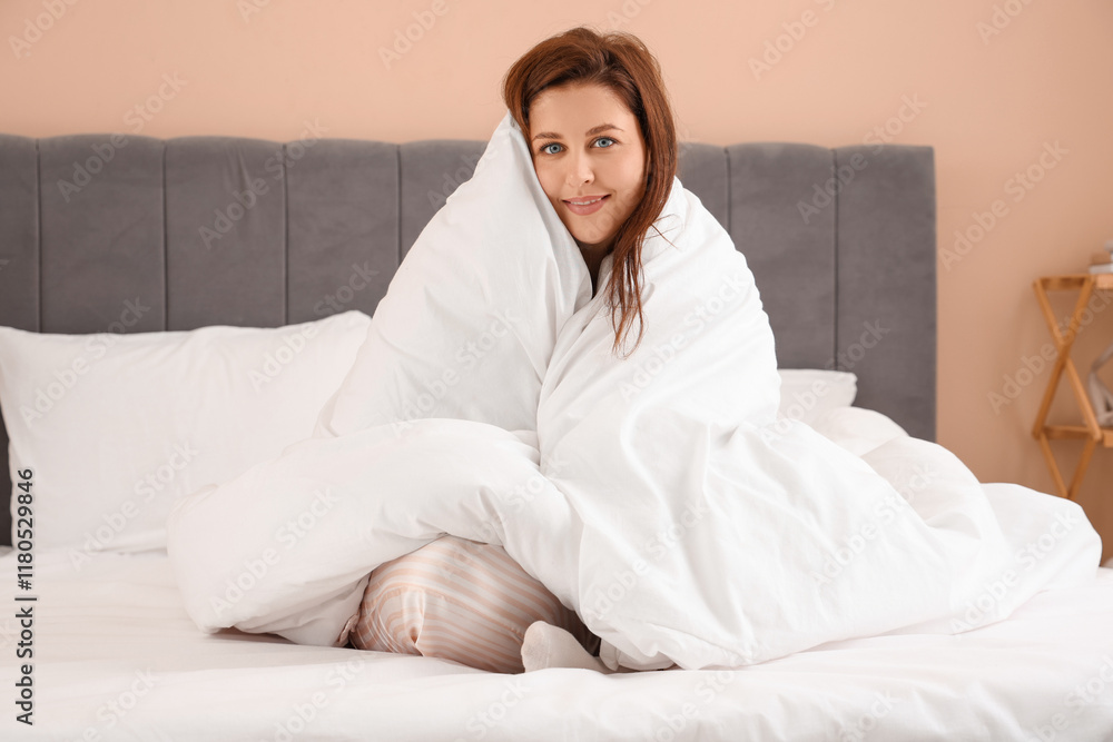 Beautiful young woman with cozy blanket sitting on bed at morning Beautiful young woman with cozy blanket sitting on bed at morning
