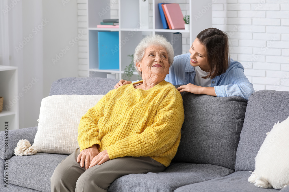 © Pixel-Shot - Young nurse and senior woman sitting on sofa at home