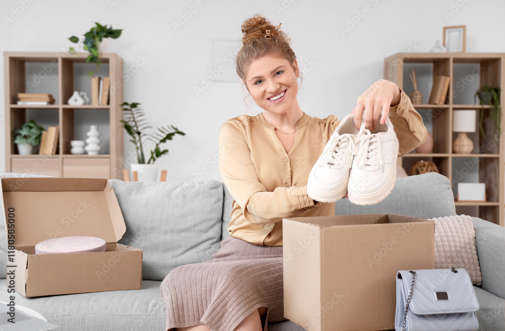 Young woman unpacking parcel box with new sneakers on sofa at home Young woman unpacking parcel box with new sneakers on sofa at home