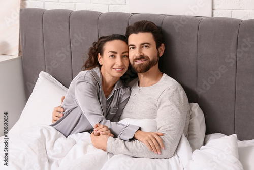 Happy couple hugging on bed...