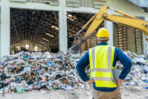 фотографія Recycling industry engineer monitoring loader machine performance on a laptop, surrounded by stacks of recyclable materials at waste separation plant