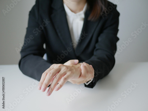 A young Asian woman working at the office feels pain in her wrists from typing from a laptop for a long time. Pain and numbness in the wrist Health care and medical concept