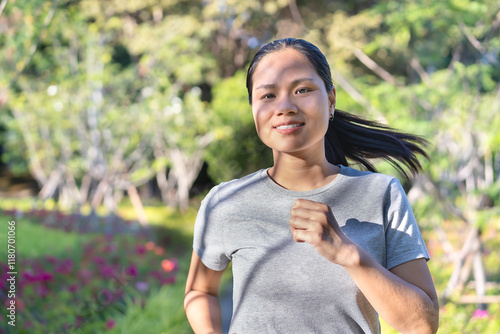 Happy young woman jogging outside in the autumn park. Burning calories with cardio exercise involves patience, practice, and good manners. Exercise concept Fitness and sports activities. photo