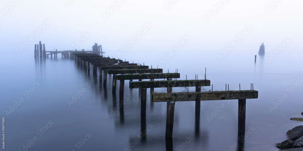 Naklejka premium Hauntingly beautiful abandoned pier stretching into misty tranquil waters evoking a sense of solitude timelessness and reflection as it merges with the serene fog creating a peaceful dreamlike scene