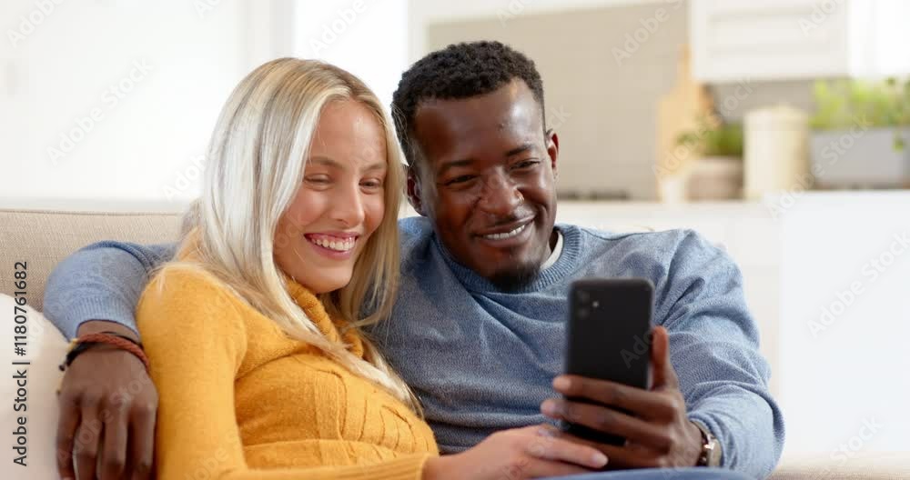 Happy diverse couple at home sharing joyful moments on smartphone, smiling together Happy diverse couple at home sharing joyful moments on smartphone, smiling together