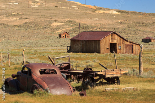 An old car is parked in a field next to a barn photo