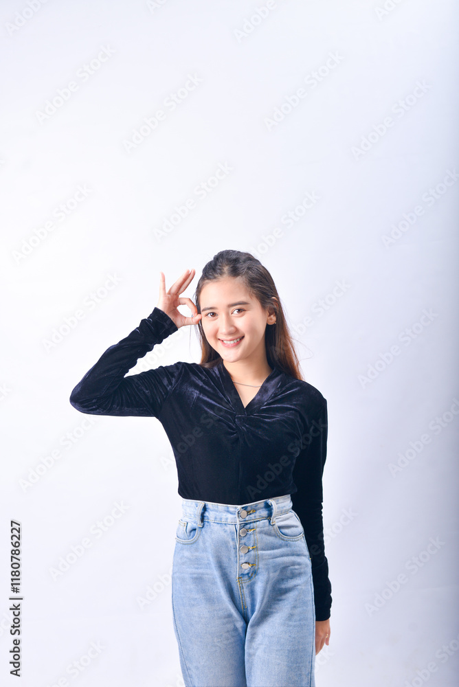 A young Asian Woman in a Black Velvet Top and Denim Jeans making expressive gestures Isolated on white background A young Asian Woman in a Black Velvet Top and Denim Jeans making expressive gestures Isolated on white background