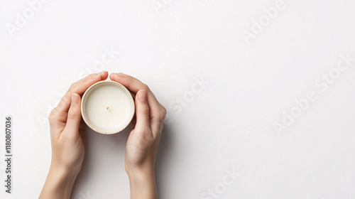 woman holding white candle in white bowl with hands on white background  relaxing spa concept