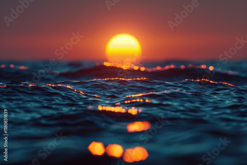 Out of focus sun setting over the ocean glowing orange with dark blue background