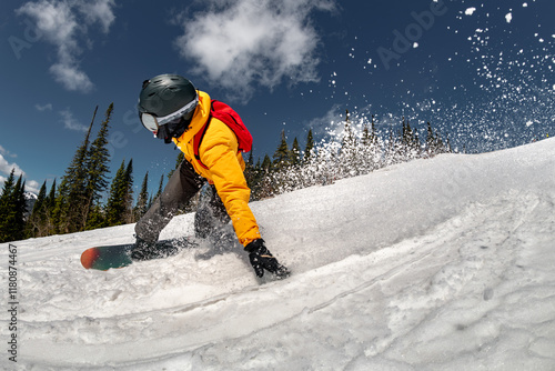 Fast snowboarder in bright yellow jacket is riding at ski slope at big speed. Ski resort vacations concept photo