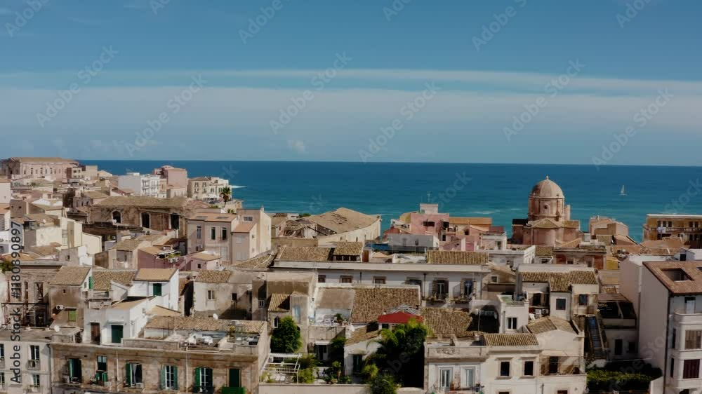 Drone shot flying sideways above historic buildings in the island of Ortigia, Syracuse. Medieval old town buildings from above with Mediterranean sea in the background. UNESCO world heritage site. Drone shot flying sideways above historic buildings in the island of Ortigia, Syracuse. Medieval old town buildings from above with Mediterranean sea in the background. UNESCO world heritage site.