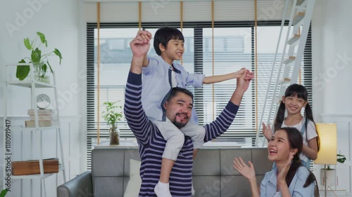 Asian Father lifting kid in air in the living room having fun, playing and enjoying morning together at home.
