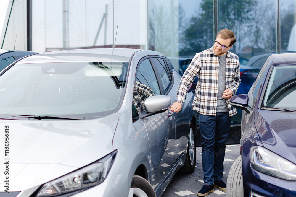 Young bearded man embracing his new car at the dealership smiling joyfully Young bearded man embracing his new car at the dealership smiling joyfully