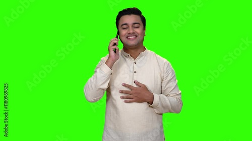 A young man is talking over the phone happily. A green screen video shoot.