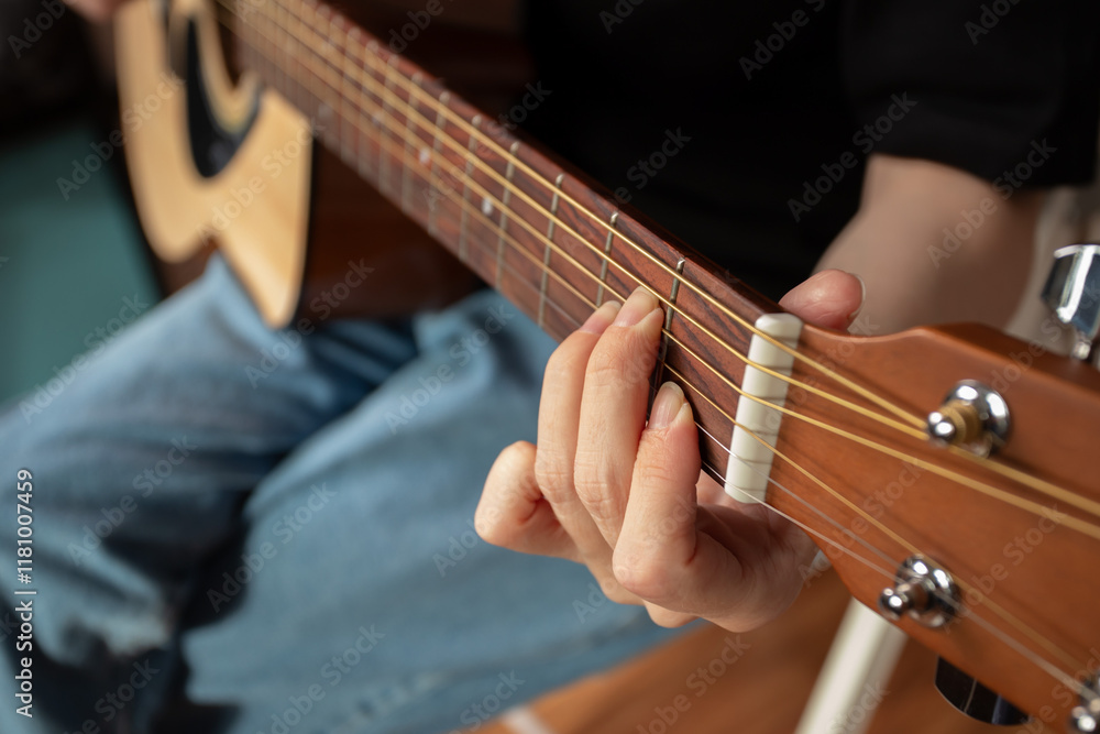 Fototapeta premium Hand Playing Acoustic Guitar Close-Up, performer practicing chords, strumming strings indoor