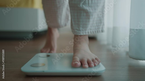 Close up a woman's bare feet stepping onto a digital weighing scale in the morning at home. Healthy lifestyle and weight awareness concept