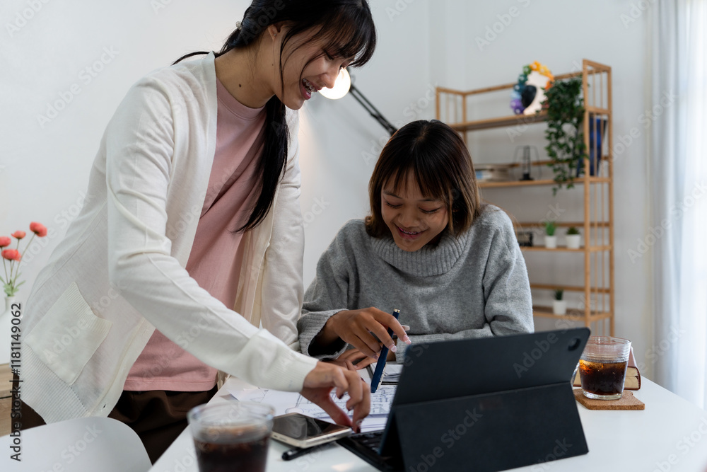 Female higher education student using laptop and studying book in home, Online learning. Female higher education student using laptop and studying book in home, Online learning.