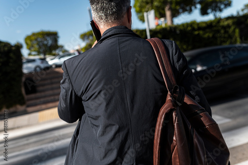 Back view of traveler talking on phone near urban crosswalk photo