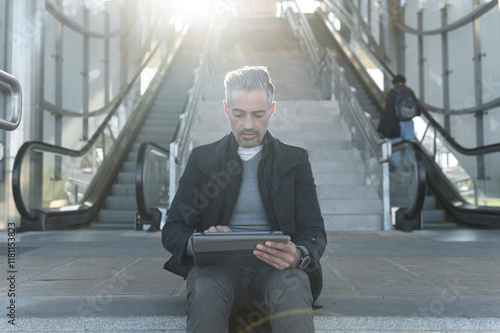 Businessman using digital tablet at train station stairs photo